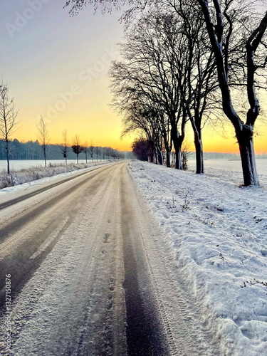 Car tracks on snow covered road by the coast of North sea in Greifswald,Germany just before sunset.