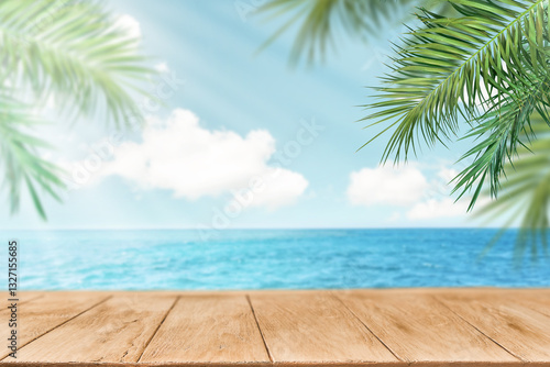 Fototapeta Naklejka Na Ścianę i Meble -  Summer sea and seascape with palm branches, sun and clouds with empty wooden table space for text. Defocus background. Blurred travel and vacation backdrop. Abstract summer background design element.