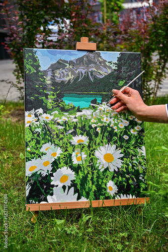 Tableau sur toile A colorful painting on an easel in a peaceful outdoor setting, with a brush nearby, capturing the process of creating art in nature