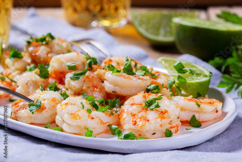 Shrimp cooked with garlic and herbs, served with beer and lime on a wooden table.