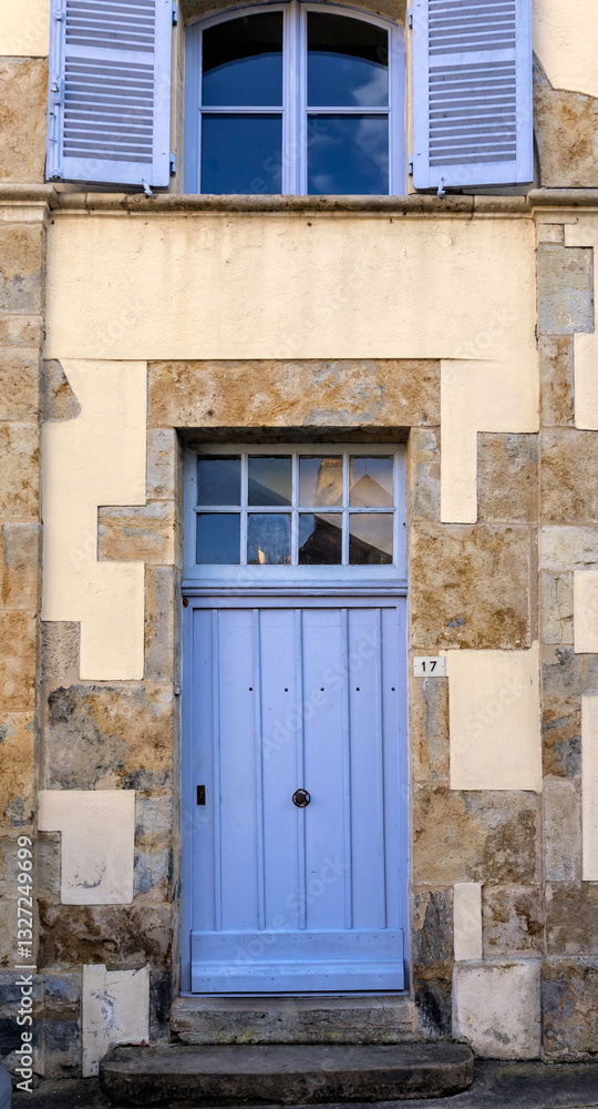 Fototapeta premium Old building facade featuring wooden door, iron balcony, and geometric stone wall pattern. For the background of your photos and collages