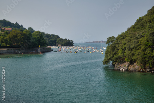 Image of fishing and recreational boats with the island of Izaro in the background, in the waters of the Cantabrian Sea, located on the coast of the province of Vizcaya. photo