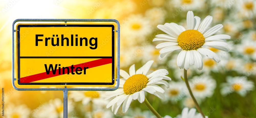 Ein Ortsschild steht vor einer Blumenwiese mit der Aufschrift Winter und Frühling