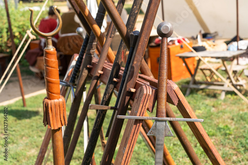 Фотография Medieval swords displayed on wooden rack at reenactment event