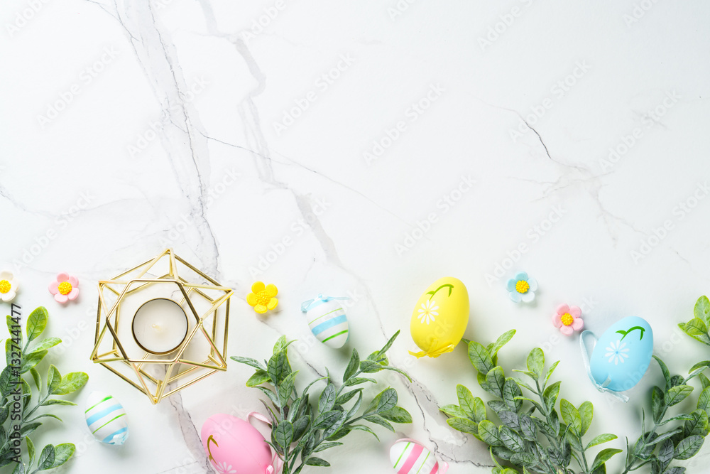 Easter composition with colored eggs and green plants on white background.
