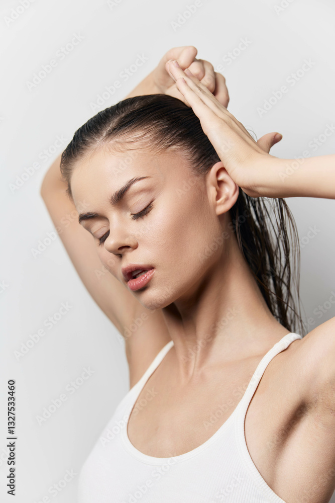 Beautiful woman with wet hair posing gracefully against a light gray background, showcasing a natural beauty and a serene expression, emphasizing personal care and self confidence