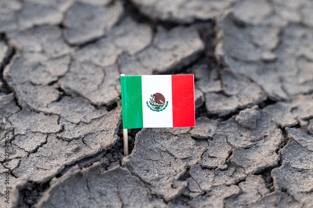 Flag of Mexico on dry cracked soil. Concept of drought in Mexico, rainless season, lack of water Flag of Mexico on dry cracked soil. Concept of drought in Mexico, rainless season, lack of water