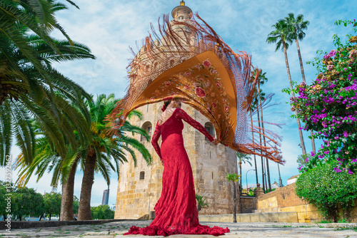 Mujer típica española bailando flamenco con una torre medieval y el cielo a su espalda. Desde la ciudad de Sevilla, Andalucía, España, Europa.	