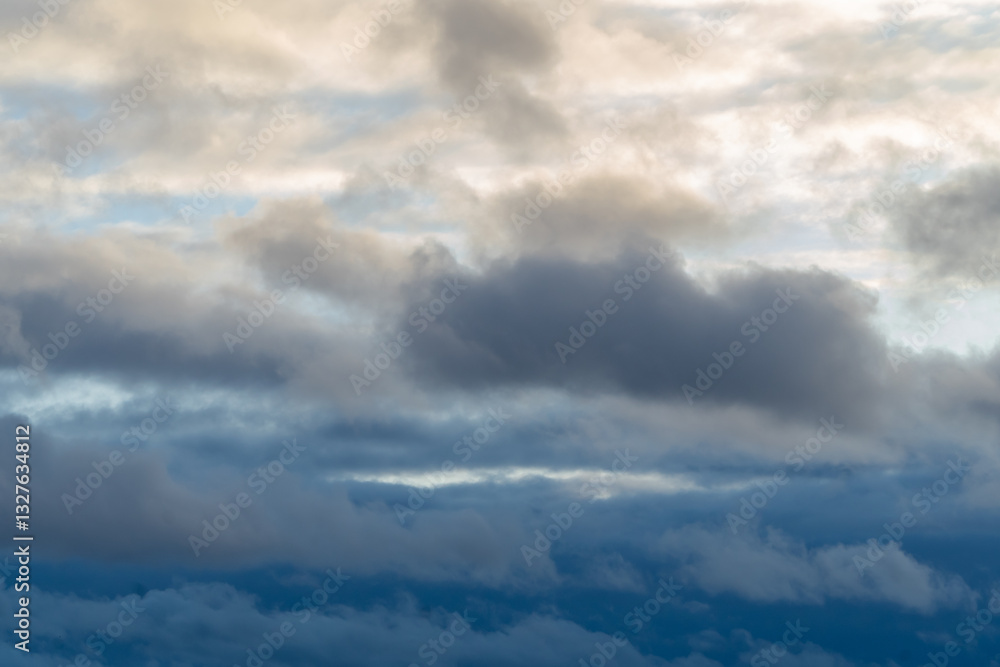 Stormy sky with dark, snowy clouds on a spring day. Clouds are floating across the sky. Dramatic clouds. Dark blue clouds swiftly floating across blue sky. Sky texture, abstract nature background.