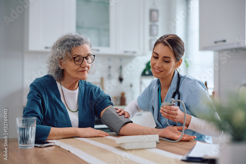 Valokuva Visiting nurse checking blood pressure of senior woman at home.