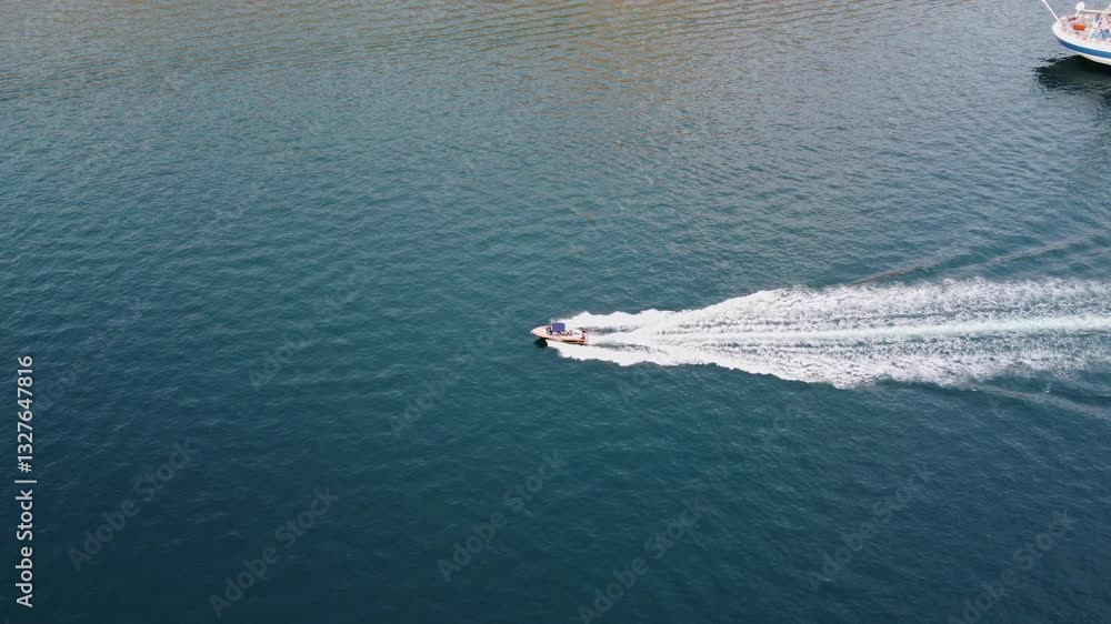 Aerial view of a motorboat proceeding at high speed, ploughing through the sea and leaving a wake behind Aerial view of a motorboat proceeding at high speed, ploughing through the sea and leaving a wake behind