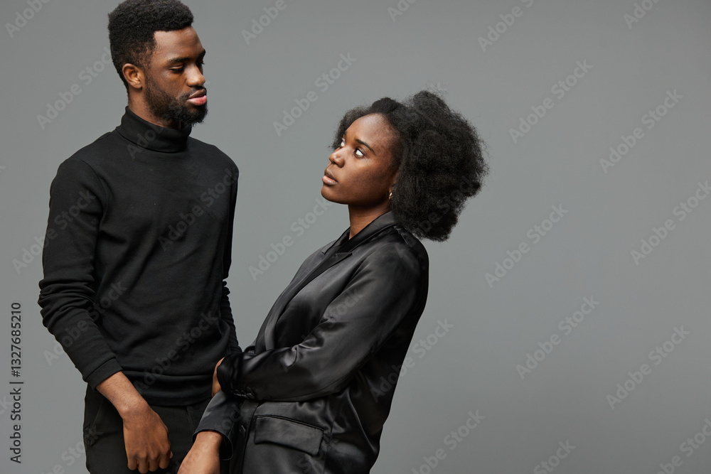 Portrait of a stylish Black couple expressing complex emotions, dressed in modern black attire against a minimalist grey background Portrait of a stylish Black couple expressing complex emotions, dressed in modern black attire against a minimalist grey background