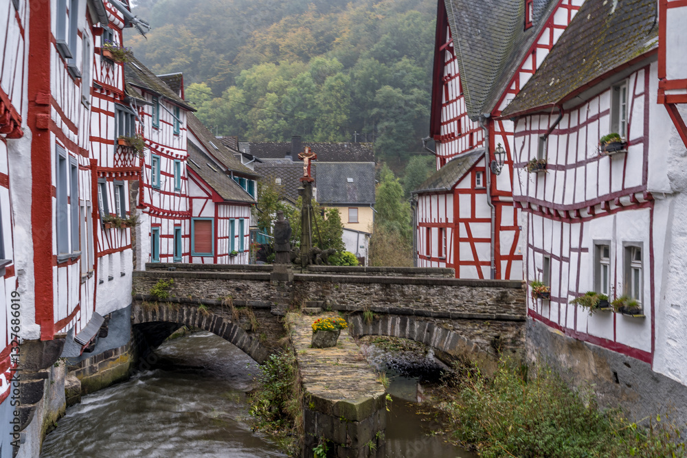 Medieval red half timbered houses in Monreal Germany with bridge above the Elzbach river with crucifix