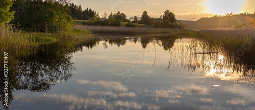 Fototapeta Naklejka Na Ścianę i Meble -  A calm lake with a sun reflecting on the water
