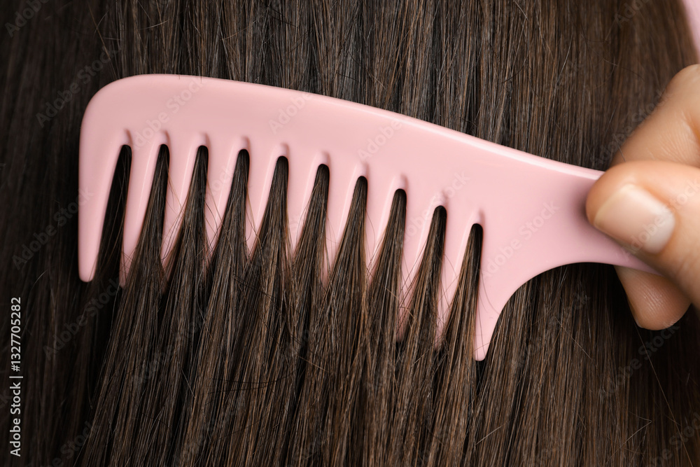 Obraz premium Woman brushing hair with plastic comb, closeup