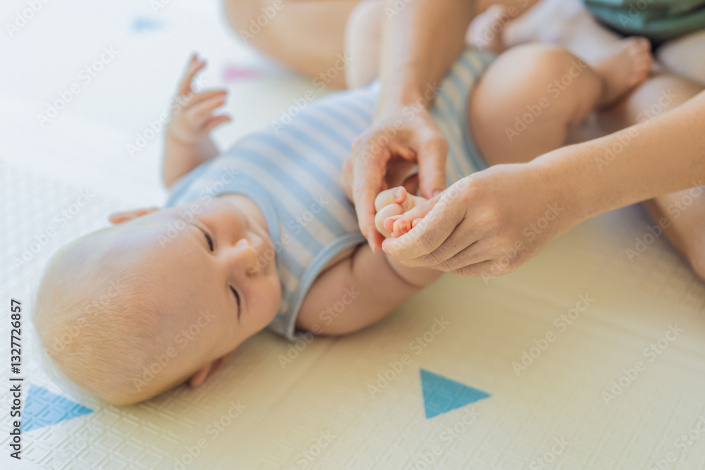A mother gently massages her baby tiny fingers and palms, promoting relaxation and stimulation. A tender bonding moment focused on care, love, and early development. Baby care, touch therapy, and