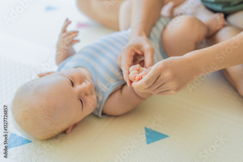 Obraz na płótnie A mother gently massages her baby tiny fingers and palms, promoting relaxation and stimulation. A tender bonding moment focused on care, love, and early development. Baby care, touch therapy, and w salonie