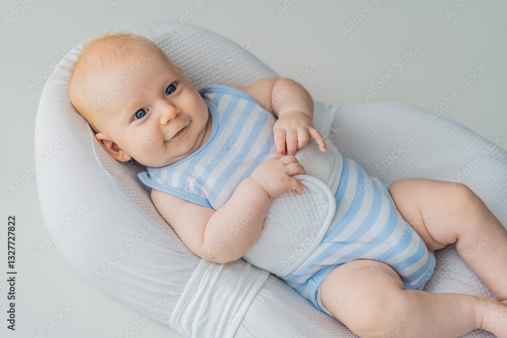 Adorable 3-month-old baby lying safely in a cozy infant cocoon secured with a special safety belt. Comfortable and protective design for newborn care. Parenting, safety, and baby comfort concept