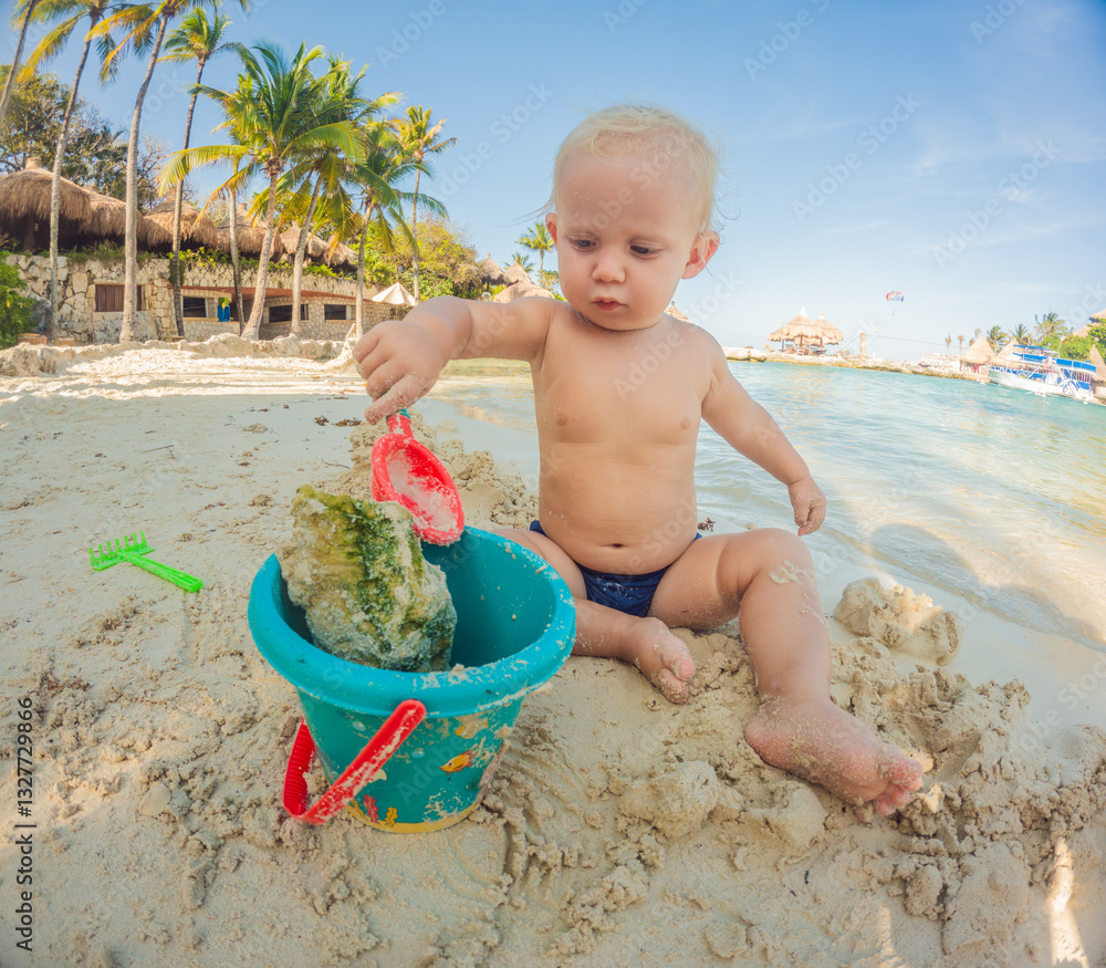 Toddler playing on the beach with a bucket and spade. Joyful childhood, seaside fun, and summer vacation concept.