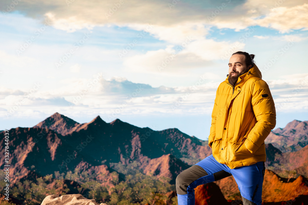 Traveler stands alone at the edge of a towering mountain range, gazing at the clouds and stunning panoramic scenery. Pleased hiker showcasing personal growth and perseverance. Traveler stands alone at the edge of a towering mountain range, gazing at the clouds and stunning panoramic scenery. Pleased hiker showcasing personal growth and perseverance.