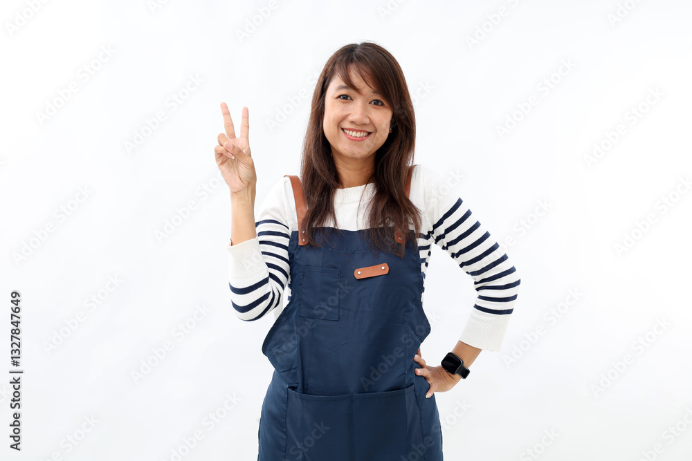 Smiling asian young woman wearing apron over white background raise fingers with showing number two. Smiling asian young woman wearing apron over white background raise fingers with showing number two.