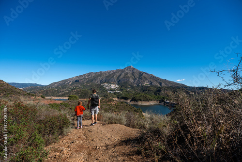 Father and son hiking with scenic mountain view and clear blue sky, La Concepcion reservoir in Marbella