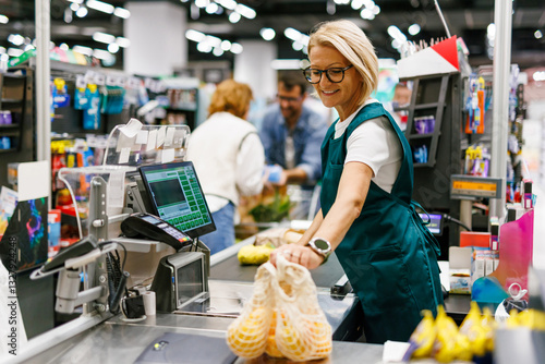 Fotografía Supermarket cashier scanning groceries at checkout counter,