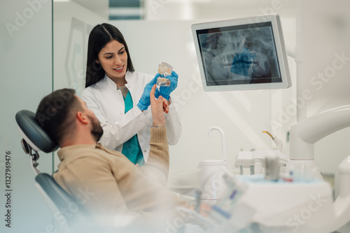 Fotografie Female dentist showing teeth model to patient in modern clinic