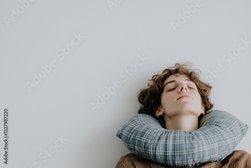 Relaxed Young Person with Neck Pillow Against Light Wall Background