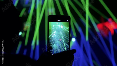 mano con un smartphone grabando un show de laser en un club