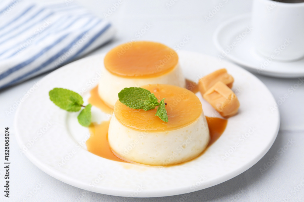 Tasty puddings with caramel sauce served on white tiled table, closeup Tasty puddings with caramel sauce served on white tiled table, closeup