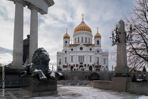 Cathedral of Christ the Savior on the background of a bronze sculpture of a lion at the foot of the monument to Alexander II the Liberator on a sunny winter day, Moscow, Russia