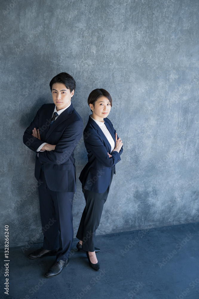 スーツで腕組みをする真剣な表情の男女の全身　コンサルタントや士業などのお仕事のイメージのカメラ目線