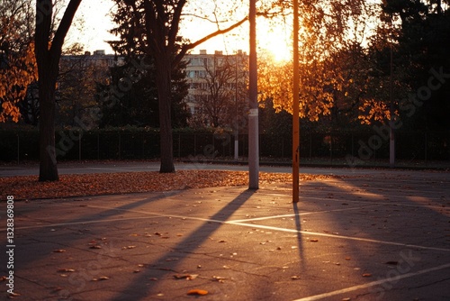 Golden hour sunlight casts long shadows across an empty parking lot, surrounded by autumnal trees