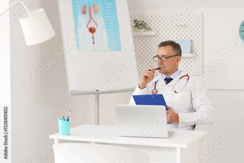 Thoughtful mature doctor working with clipboard at desk in medical office