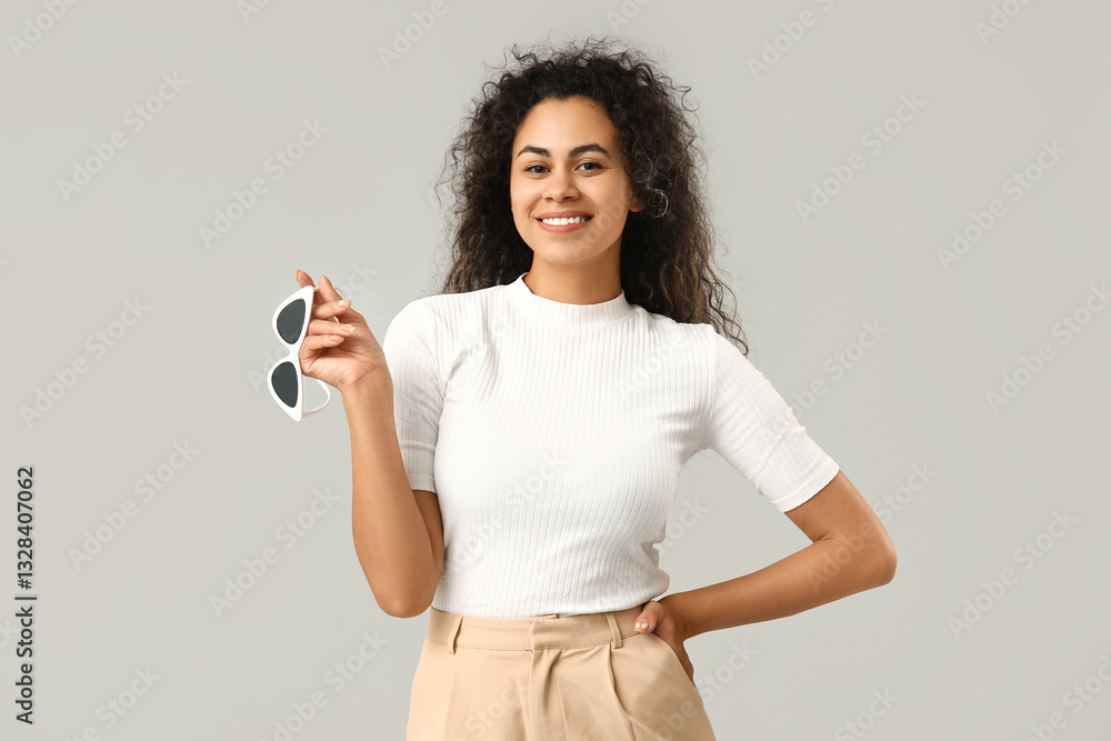 Stylish African-American woman with sunglasses on grey background Stylish African-American woman with sunglasses on grey background