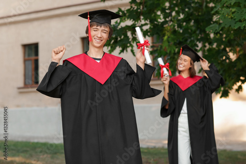 Graduating students with diplomas outdoors