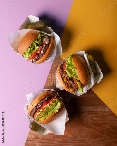 Three juicy cheeseburgers with lettuce, tomato, and cheese, served on vibrant pink and yellow backgrounds. A fun fast-food arrangement.