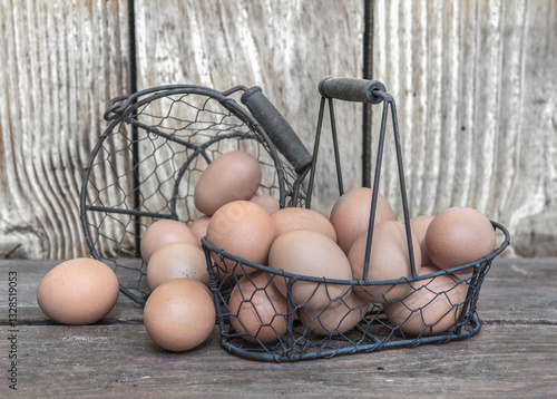 chicken eggs  in little metal baskets on a table in front of a wooden wall .