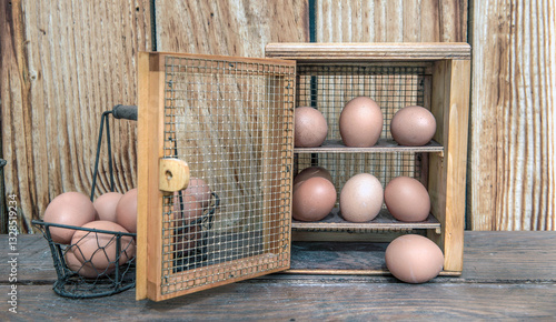 chicken eggs  in a decorative box on a table  and a little metal basket in fr...