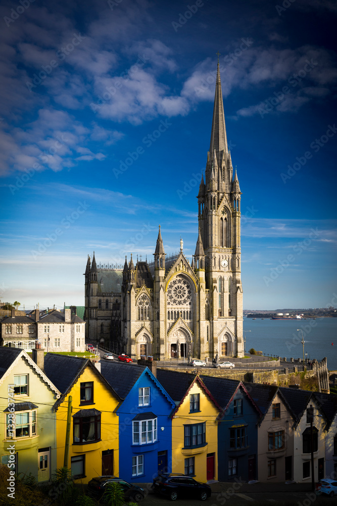 Fototapeta premium Cobh, Ireland - March 6th 2025 - Saint Colmans Cathedral and colourful houses on West View