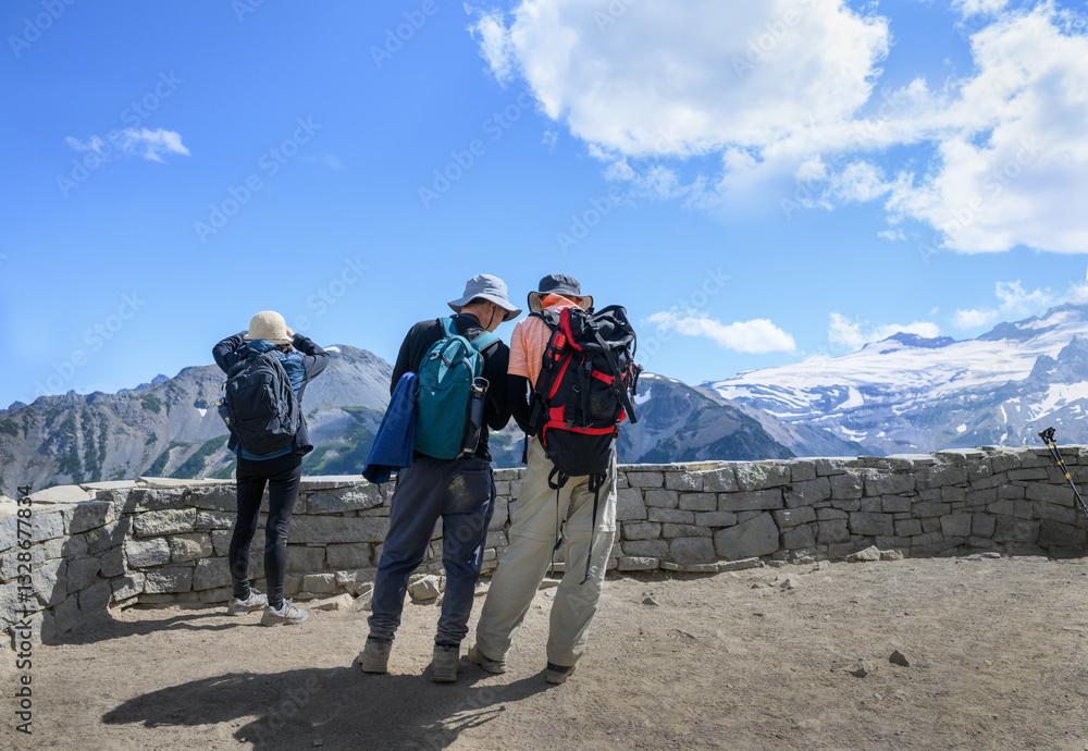 Three tourists checking route maps and taking photos using a smartphone at the overlook. Sunrise Trail. Mount Rainier National Park. Washington State.