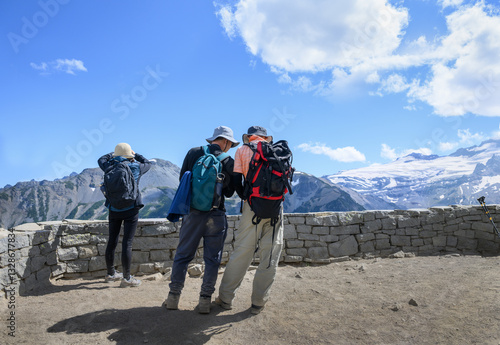 Obraz na płótnie Three tourists checking route maps and taking photos using a smartphone at the overlook. Sunrise Trail. Mount Rainier National Park. Washington State. w salonie