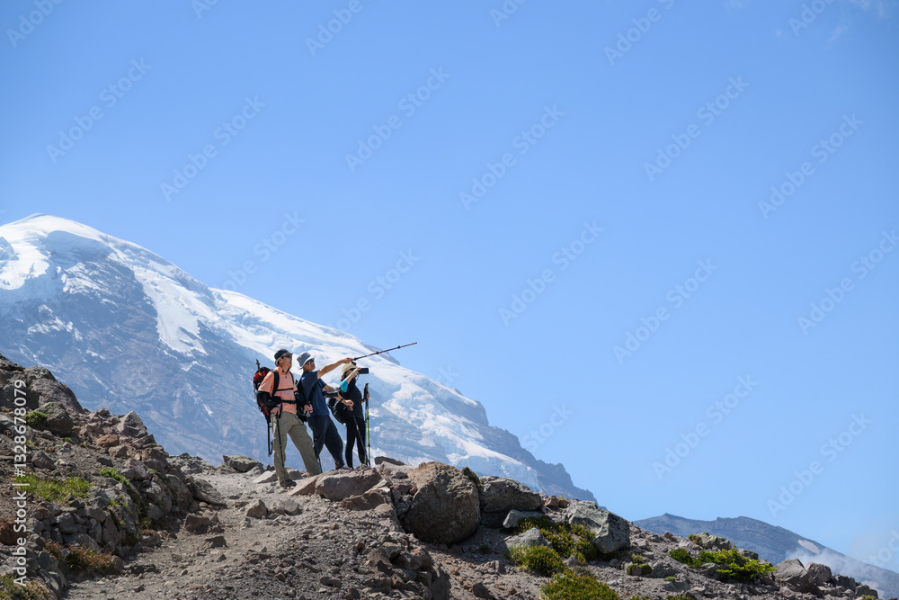 Three backpackers hiking the Sunrise Trail in summer. Mount Rainier in the background. Mt Rainier National Park. Washington State.