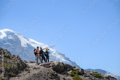 Obraz na płótnie Three backpackers hiking the Sunrise Trail in summer. Mount Rainier in the background. Mt Rainier National Park. Washington State. w salonie