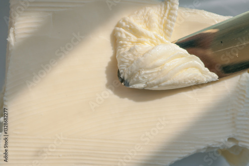 Wallpaper Mural Close-up of a knife spreading fresh butter with soft curls forming on the blade. Warm natural light highlights the creamy texture, creating a rustic and appetizing food scene Torontodigital.ca