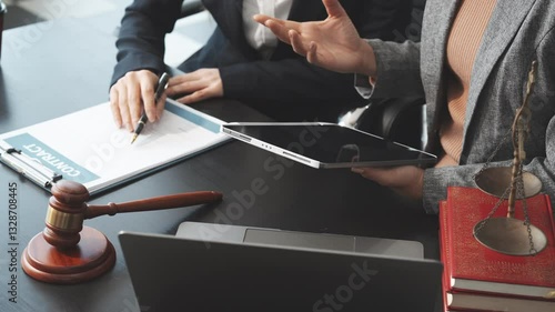 Two female lawyers in business suits meet at wooden desk, shaking hands over contract paper. wooden gavel and scales justice as discuss legal compliance, corporate law, dispute resolution.