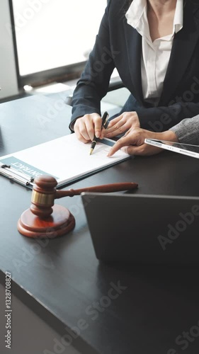 Two female lawyers in business suits meet at wooden desk, shaking hands over contract paper. wooden gavel and scales justice as discuss legal compliance, corporate law, dispute resolution.
