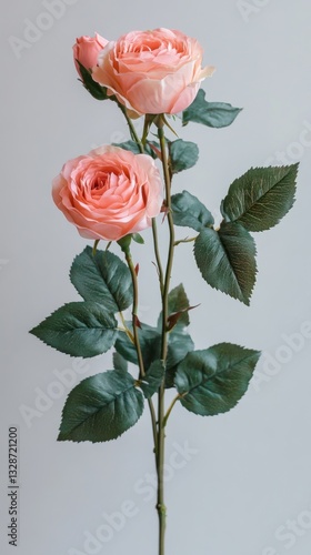 Close-up of a single stem artificial peach rose with three blossoms and lush green leaves against a light grey background.