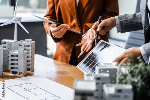 Wallpaper Mural Two businesswomen sit at a desk in a meeting, discussing property development while building a model of city tower. real estate investments, zoning laws, sustainable energy solutions. net zero Torontodigital.ca